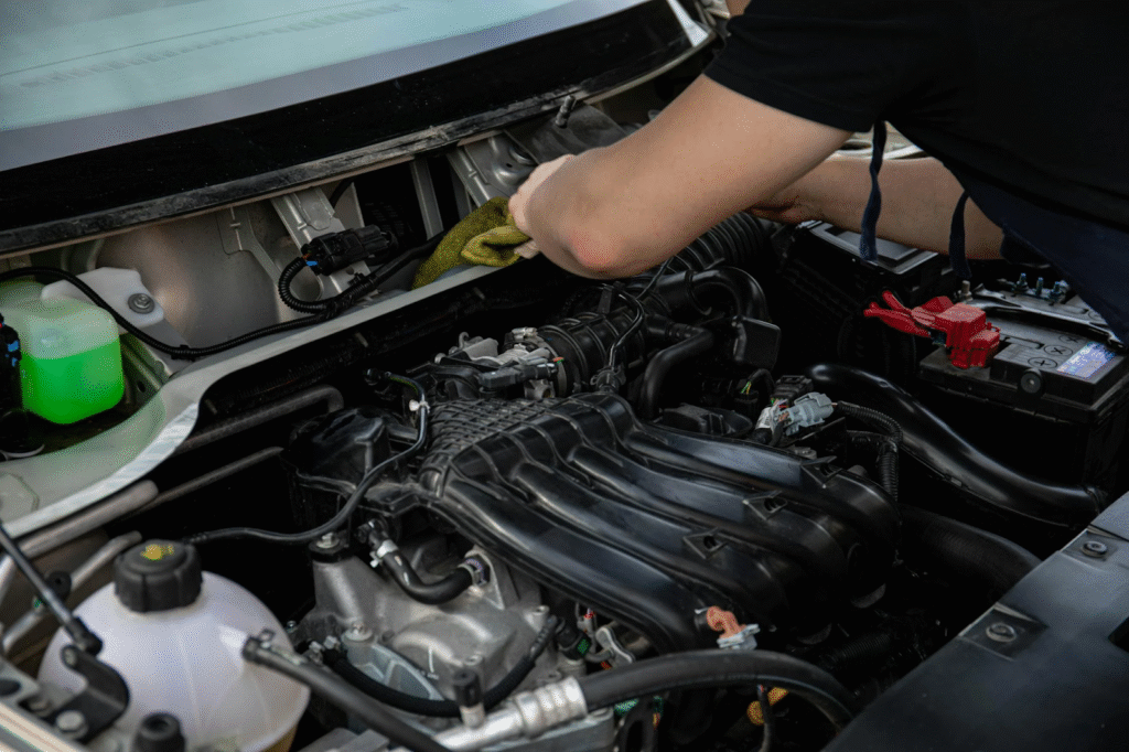 A man is working underneath a car, positioned near the wheels, focused on repairs.